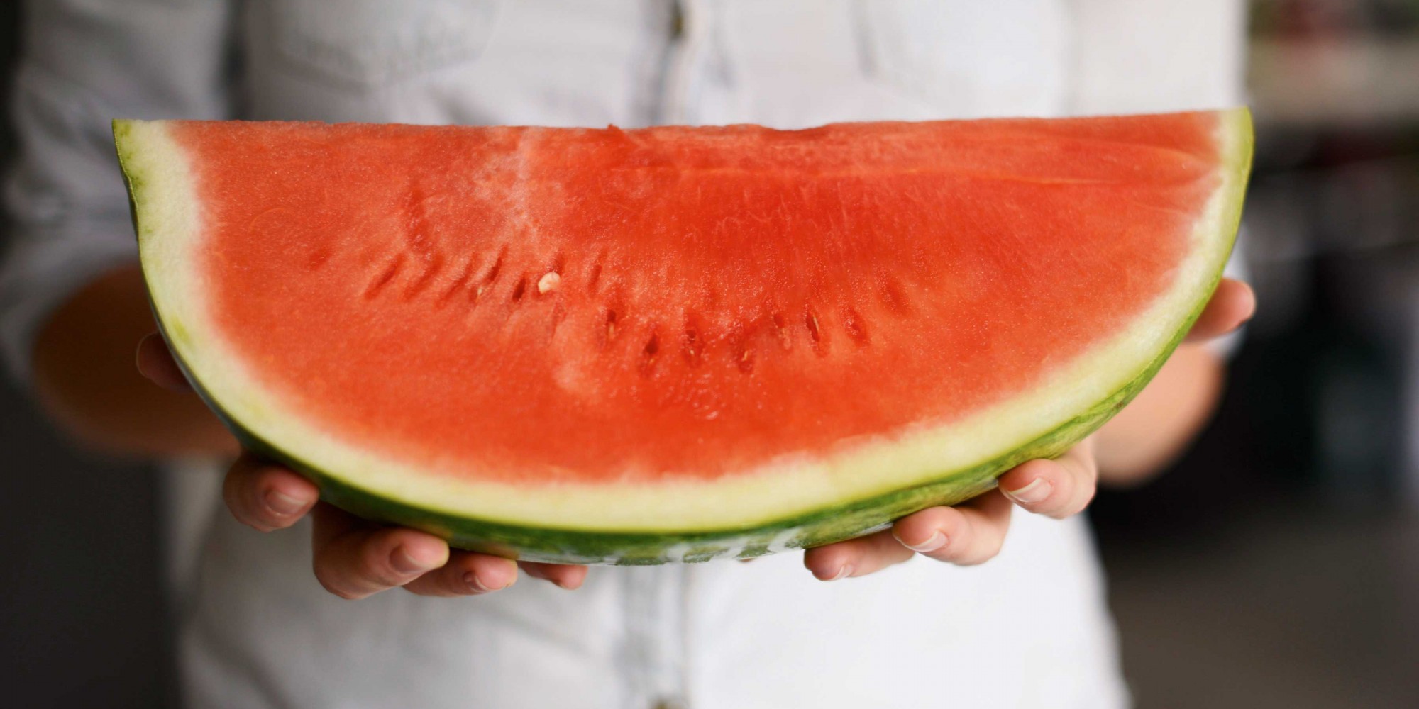 A person holding a big wedge of seedless watermelon
