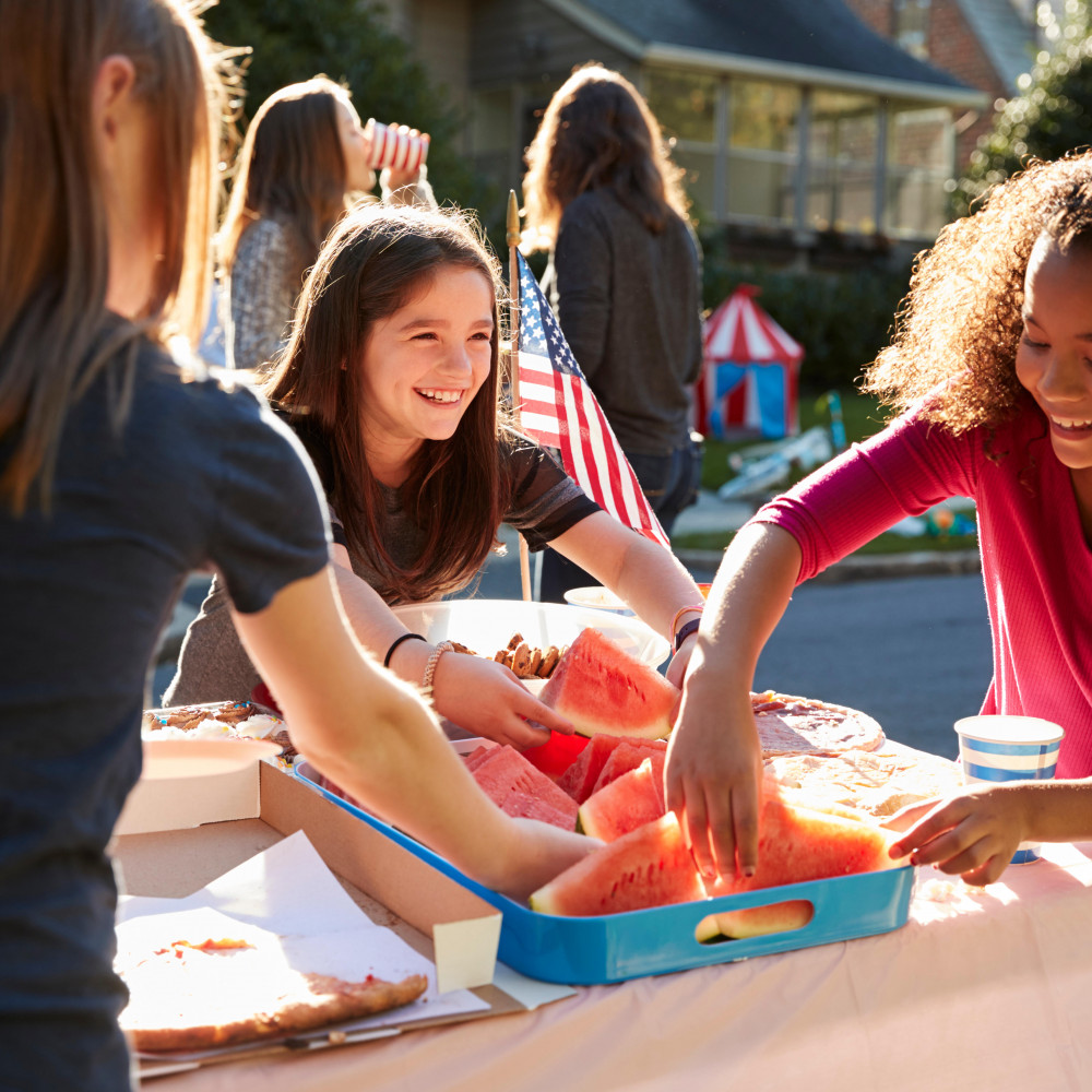 Girls serving themselves watermelon at a block party