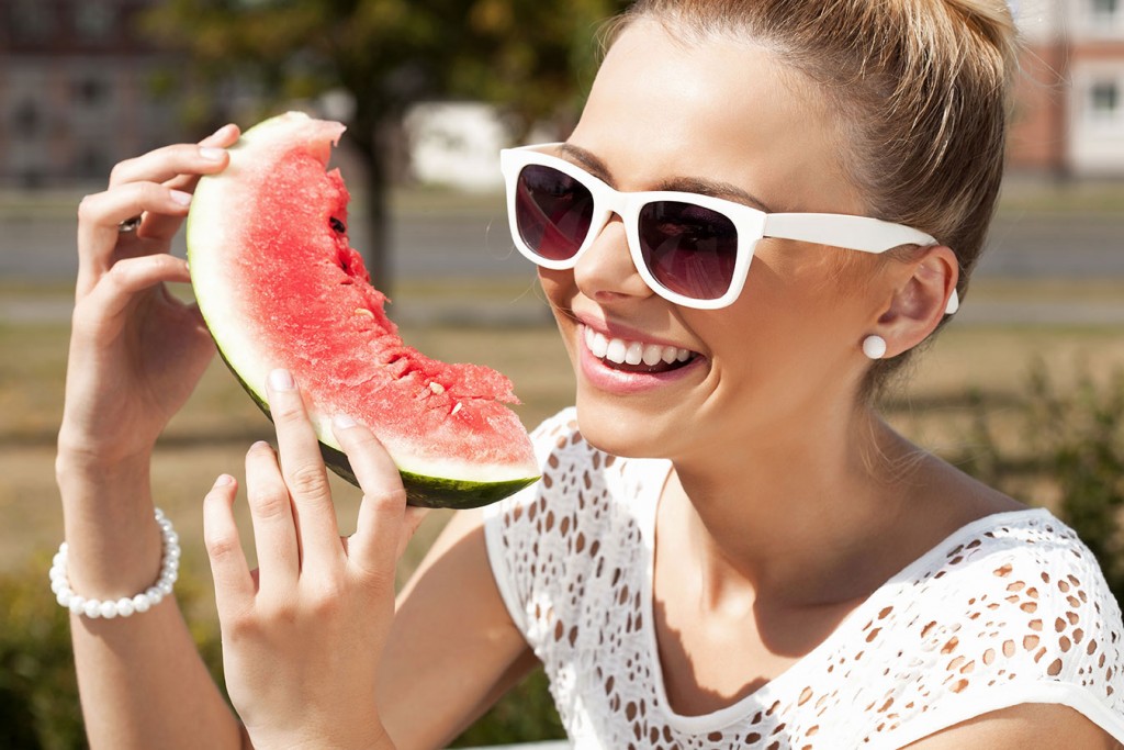 Woman eating a slice of watermelon in the summer sunshine