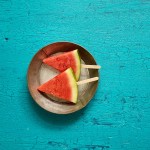 watermelon triangular cuts in metal pan on teal painted wooden background