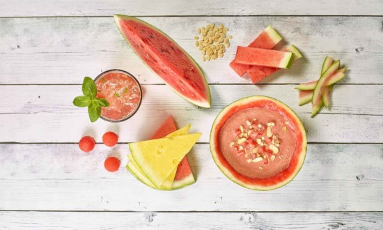 White painted wooden background with variety of watermelon, soup, rind, cuts, yellow, balls, wedges, seeds, agua fresca