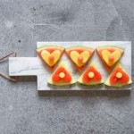 red and yellow triangular watermelon cut-out on marble cheese board