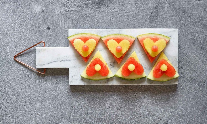 red and yellow triangular watermelon cut-out on marble cheese board