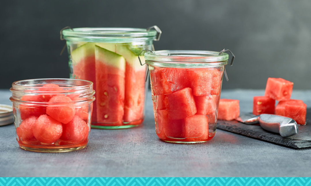 watermelon balls, chunks, sticks in jars with slate cutting board and knife on side
