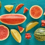 various watermelon cuts, including yellow on teal painted wooden background