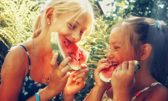 two young girls eating watermelon slices/halves
