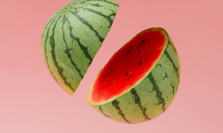 watermelon, cut in half, seemingly suspended in air with variegated pink background
