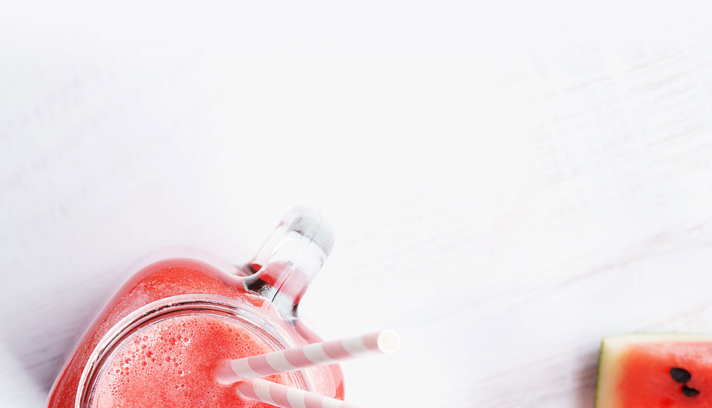 white background with handled jar of agua fresca, right corner, small portion of watermelon wedge