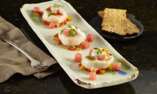 watermelon escabeche wet on rectangular plate with appetizer fork on side with brown cloth napkin. crackers on side