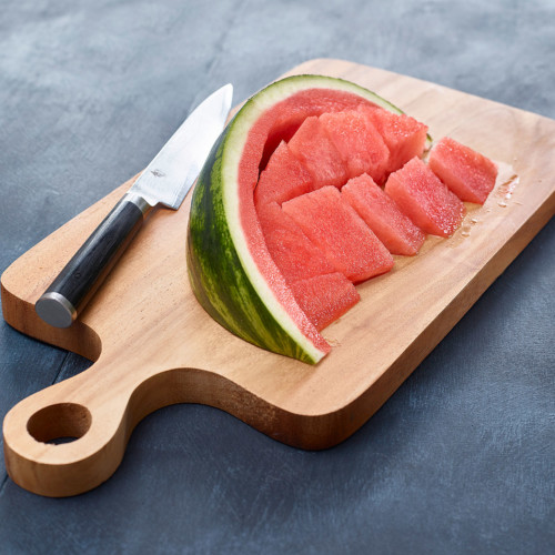 watermelon wedge with flesh cut away from rind on wooden cutting board with knife on side
