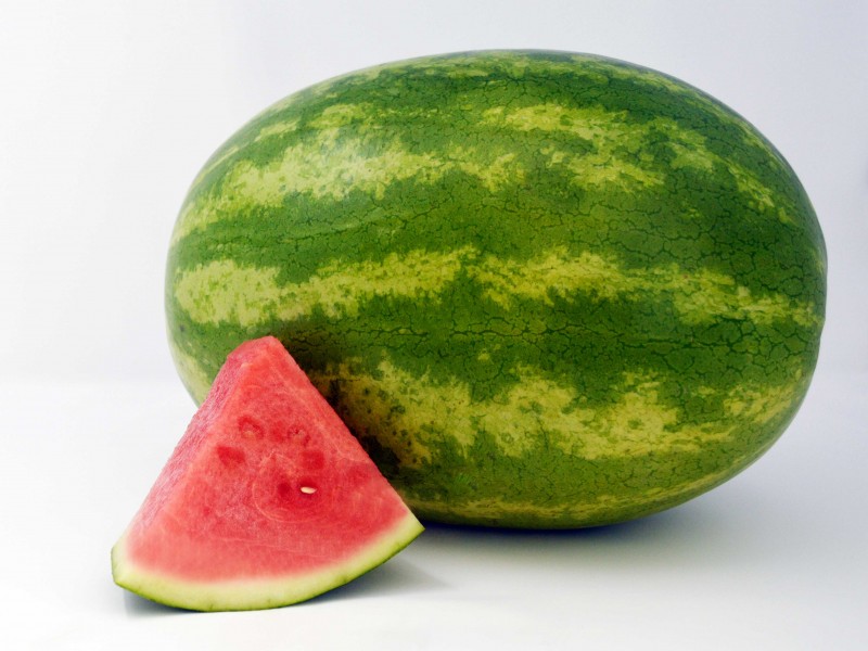 whole watermelon with triangular cut of watermelon in foreground