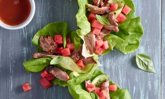 watermelon lettuce wraps with condiments and cruet of sauce set on blue-gray wooden background