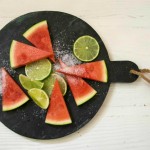 Salted Lime Slices of triangular cuts of watermelon, lime and salt on round slate "board"