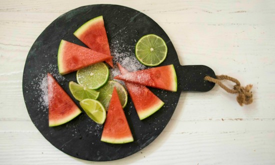 Salted Lime Slices of triangular cuts of watermelon, lime and salt on round slate 