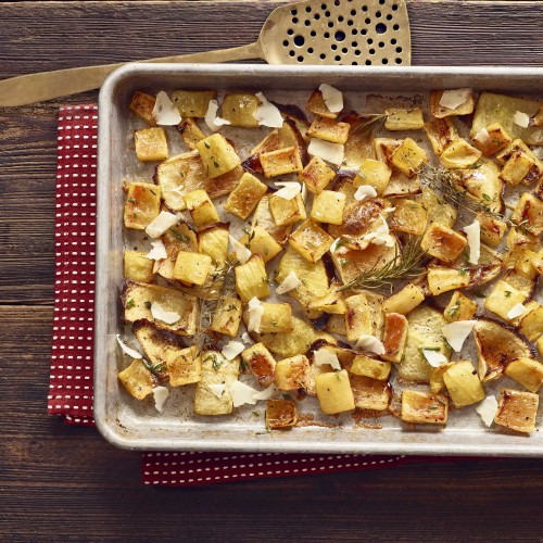 Roasted Rind Parmesan in baking pan with spatula on side. Set on red with white polkadot napkin on wooden table