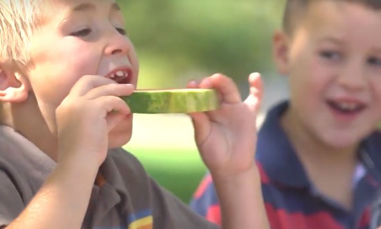 two young boys, one eating slice of watermelon, smiling