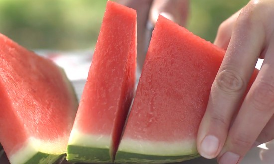 close-up of slicing of watermelon. Hands in view