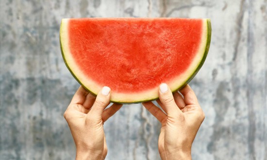 Half moon wedge of watermelon held up with two hands