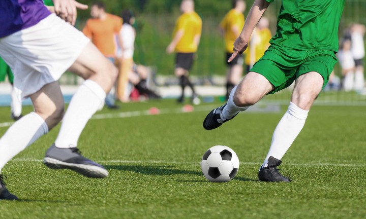 soccer game with two players in play in foreground. Other players and spectators in background