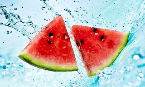 two watermelon triangular cuts being splashed with water, 