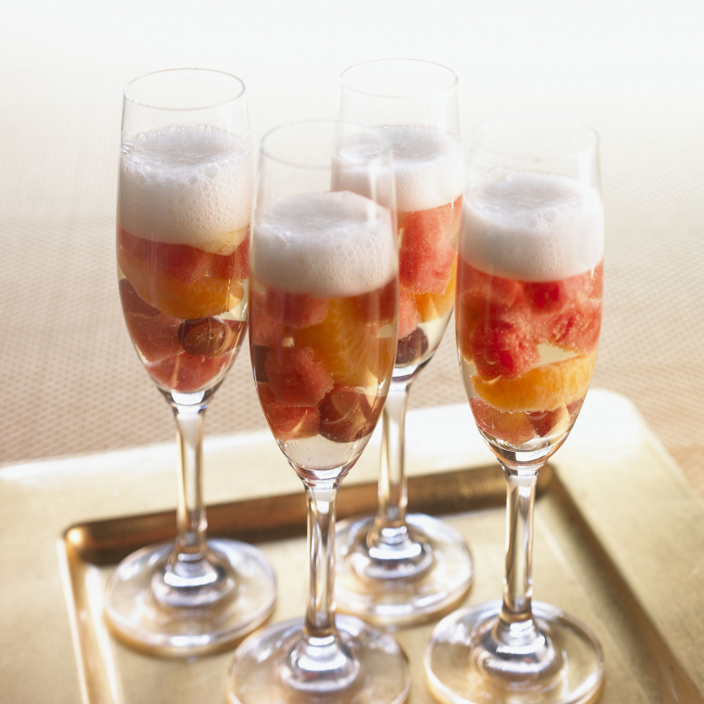 Four Watermelon Champagne Sangria served in champagne flutes, filled with cut fruit.