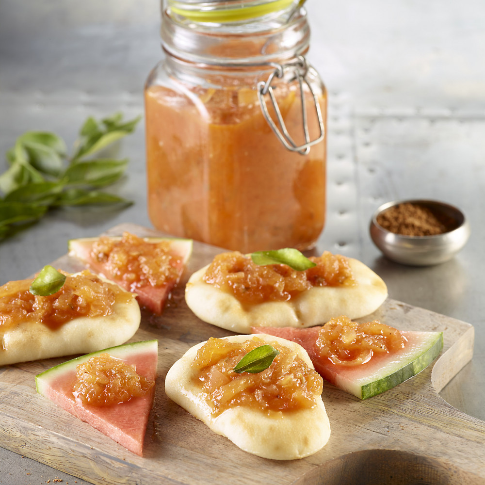 Cutting board with chutney in a jar served on pitas