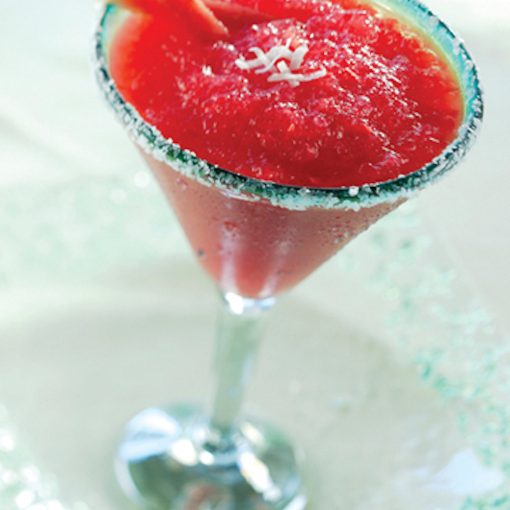 Watermelon Coconut Margarita served in martini glass, sugar rimmed with shredded coconut and two watermelon stix as garnish.