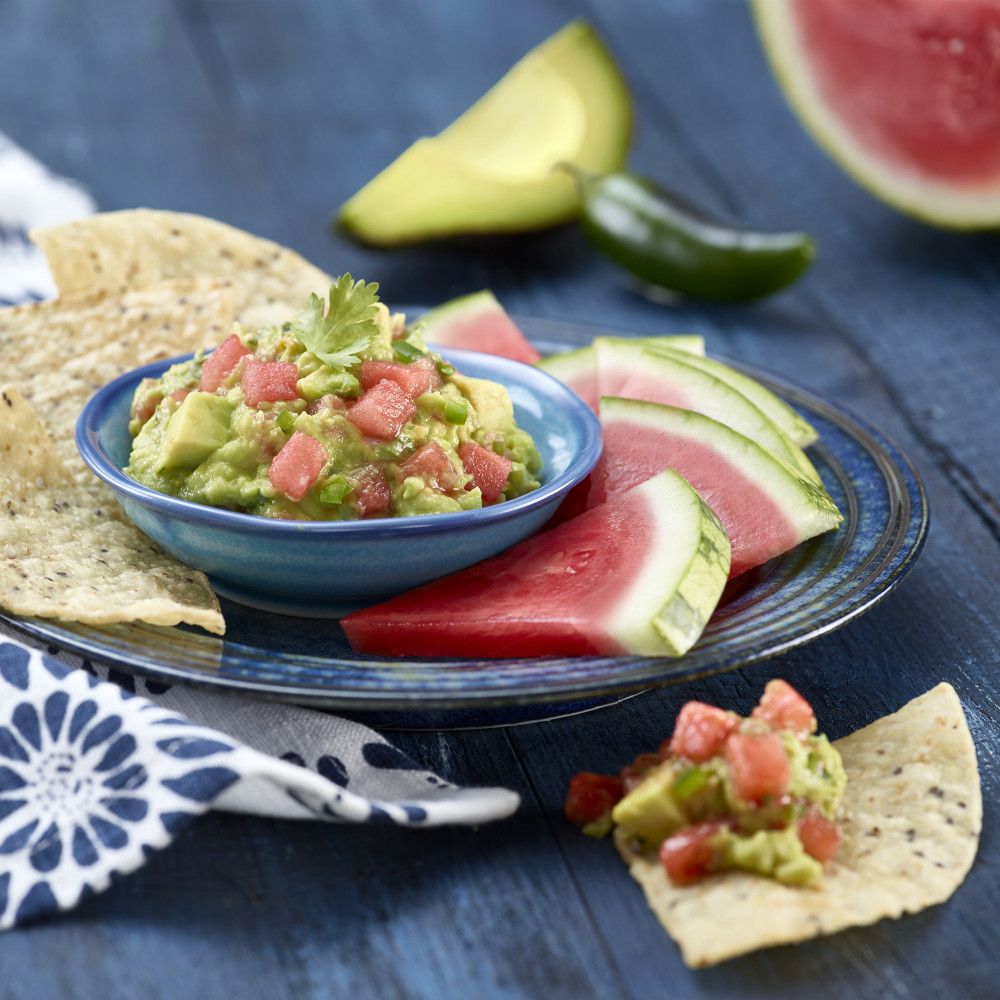 plated dish with guacamole in serving bowl with chips and watermelon triangles with rind