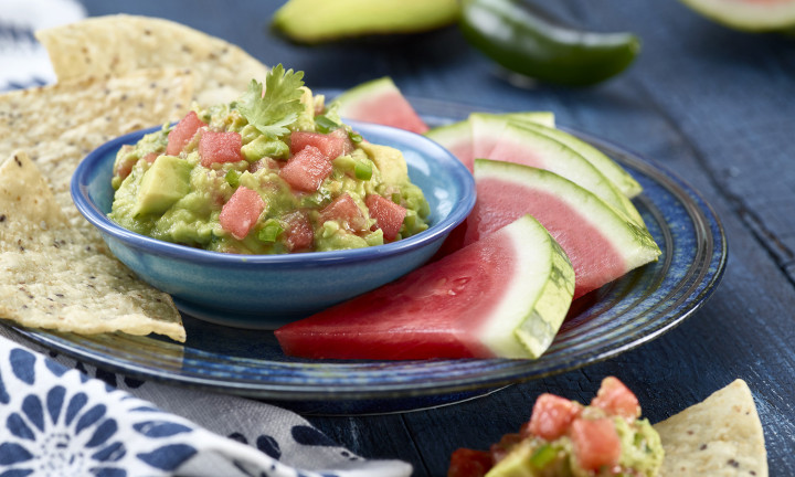 plated dish with guacamole in serving bowl with chips and watermelon triangles with rind