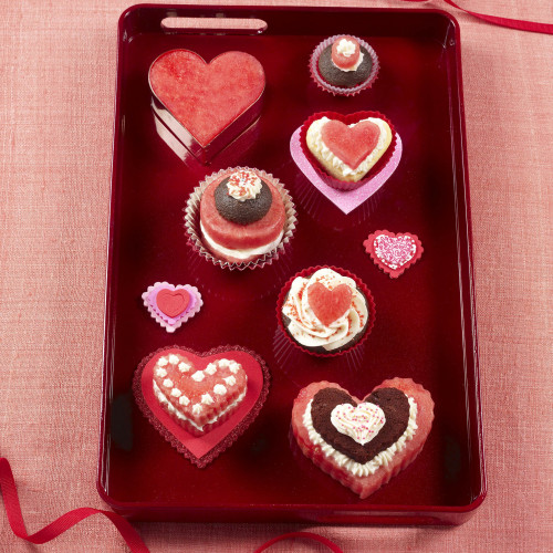 Watermelon cutouts, heart shaped & round, some with brownie set on red serving tray. Light red tablecloth with red ribbon above and below tray