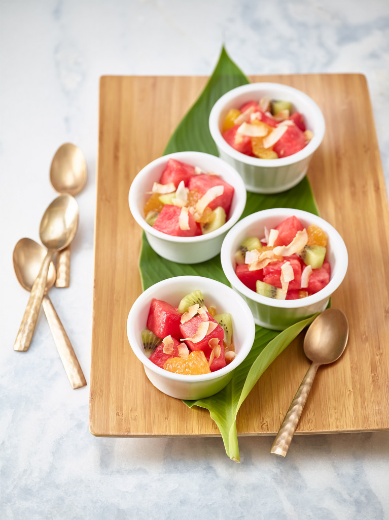 Island Fruit Salad served in three white ramekins on wooden cutting board with spoon on cutting board and 3 spoons on side.