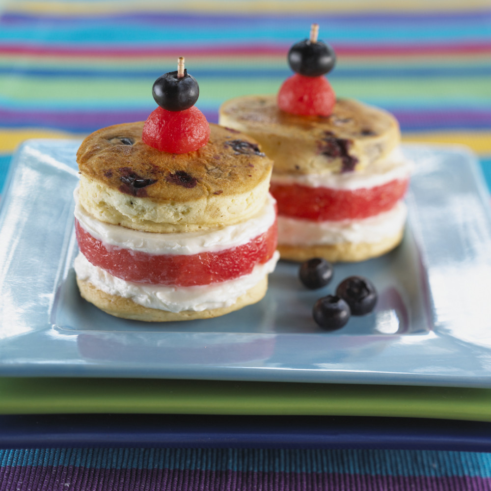 Two Sandwich Cookies set on a square aqua plate, garnished with a watermelon ball and blueberry.