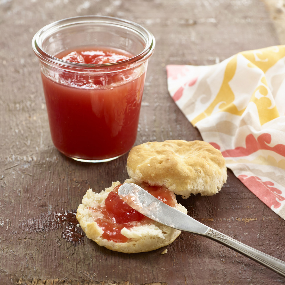 jar of watermelon lemonade jam with sliced biscuit and spreading knife