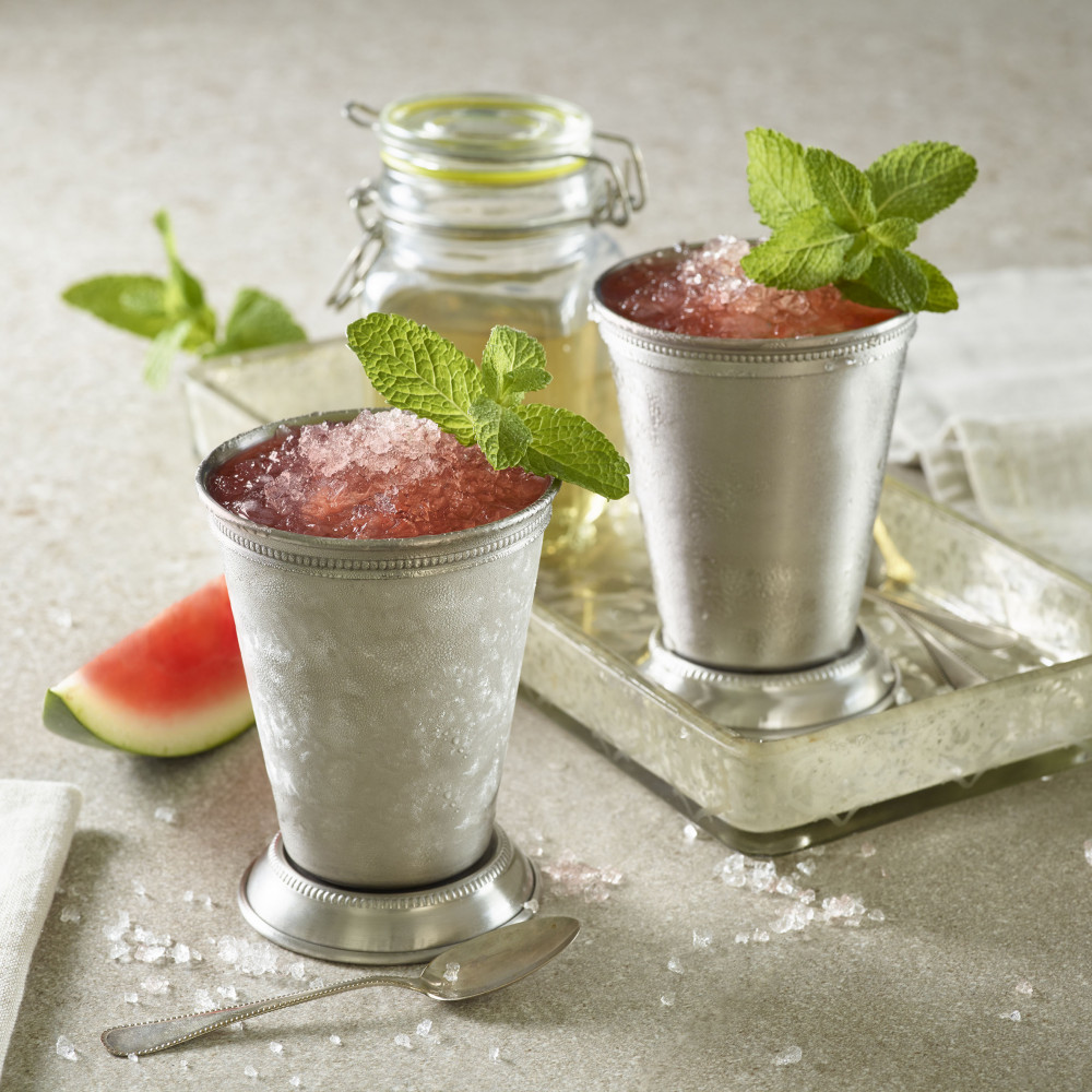 Two Mint Juleps served in stainless cocktail "glasses", garnished with mint leaves.