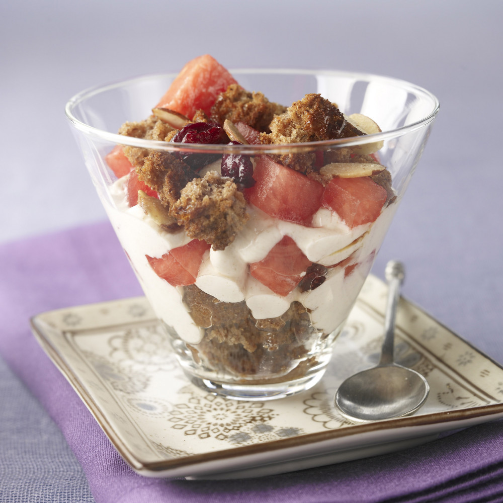 One Watermelon Muffin Crumble Parfait in clear glass served on dish with spoon alongside.