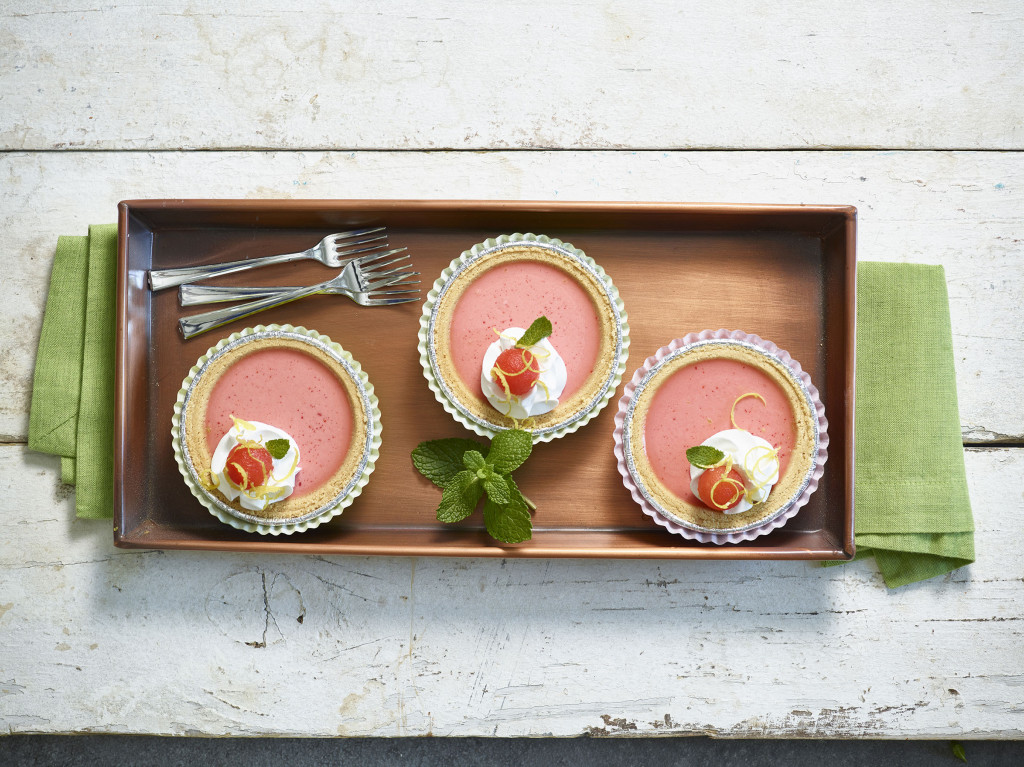 Three Watermelon Pies served on a wooden serving tray with mint, whipped cream, lemon zest and watermelon ball as garnishes.