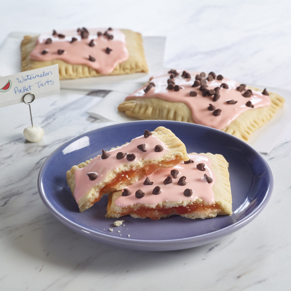 Tarts on a blue stoneware plate on a marble countertop. Other tarts on paper napkins on side.