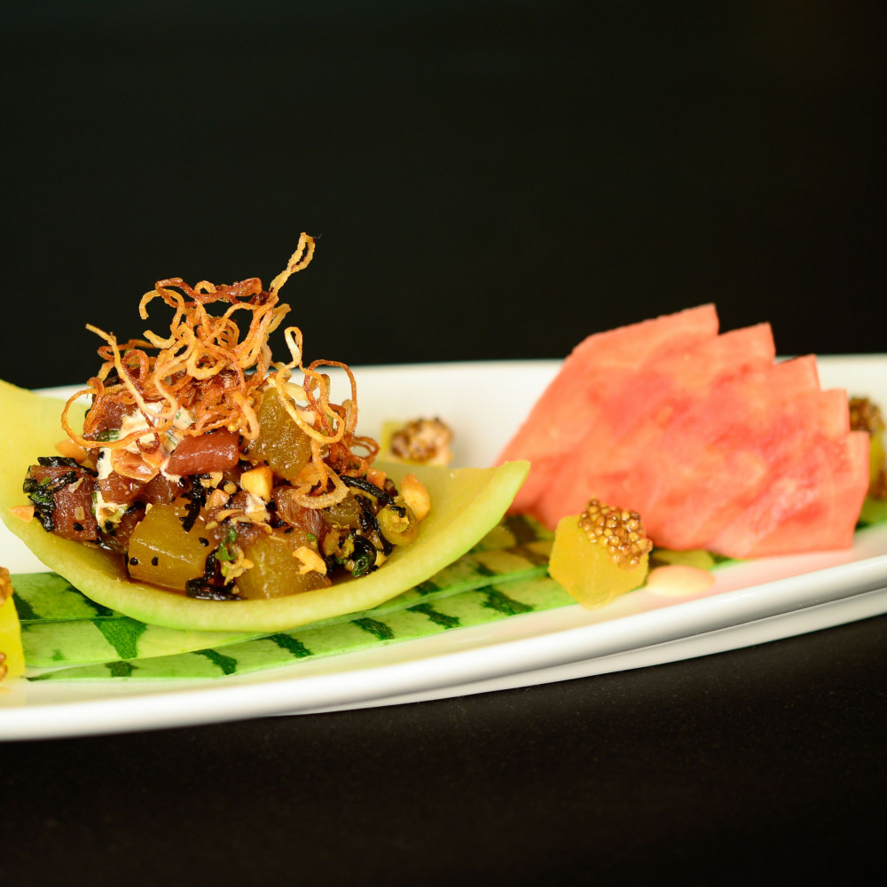 Watermelon & Tuna Poke served on boat shaped plate garnished with yellow watermelon, yellow mustard seeds.