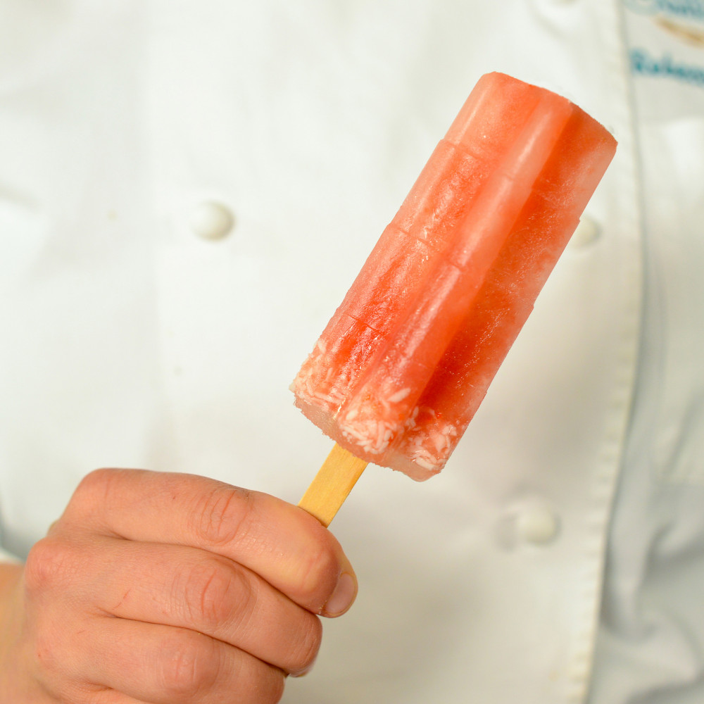 Popsicle on a stick, held by chef in white chef's coat.