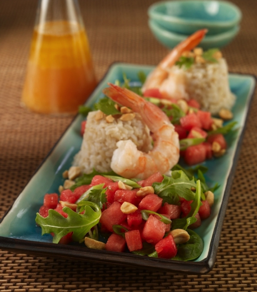 Thai Watermelon Salad served on rectangular teal colored plate, topped with shrimp. Cruet of dressing in background.