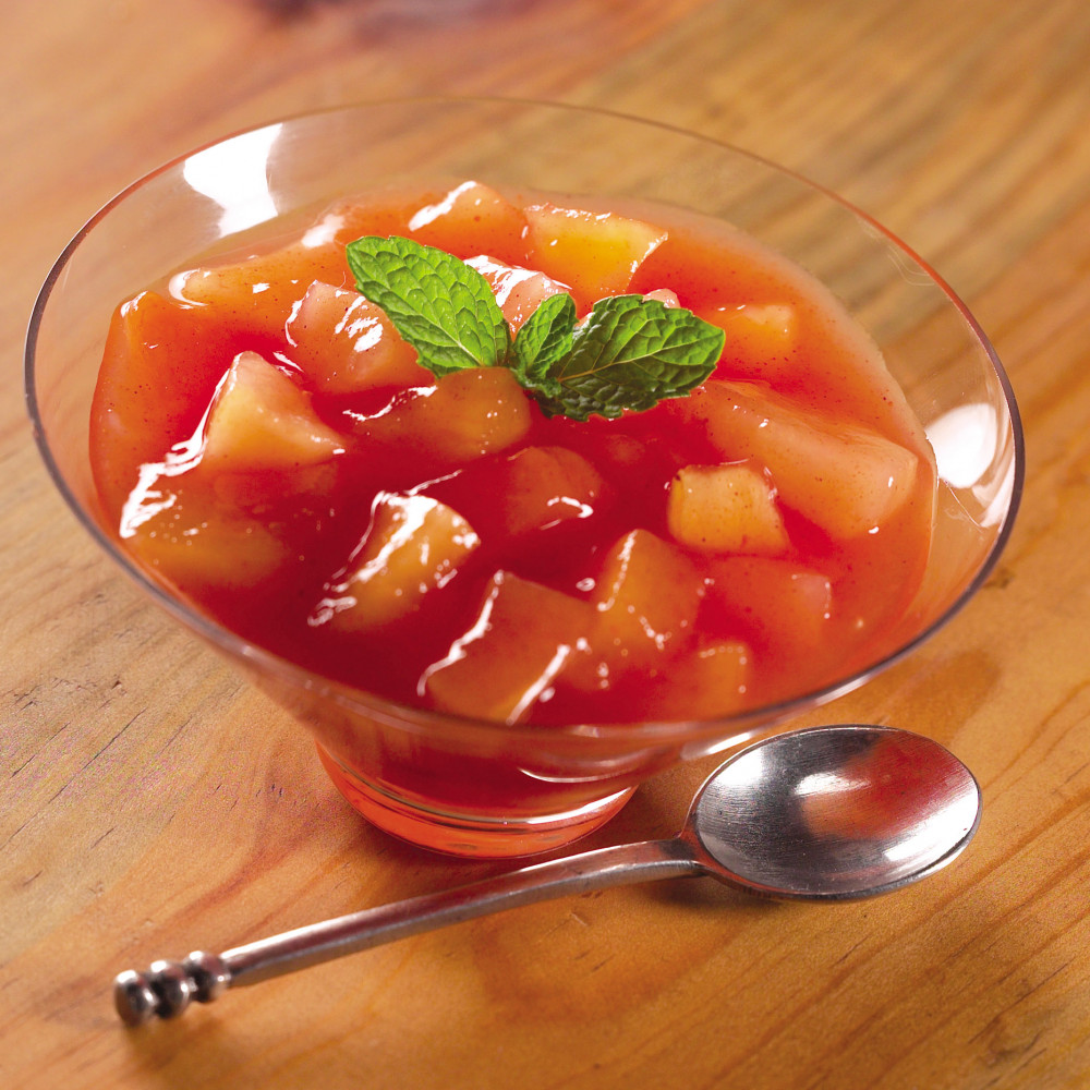 Watermelon Fruit Compote in clear dessert dish with mint garnish and spoon on side.