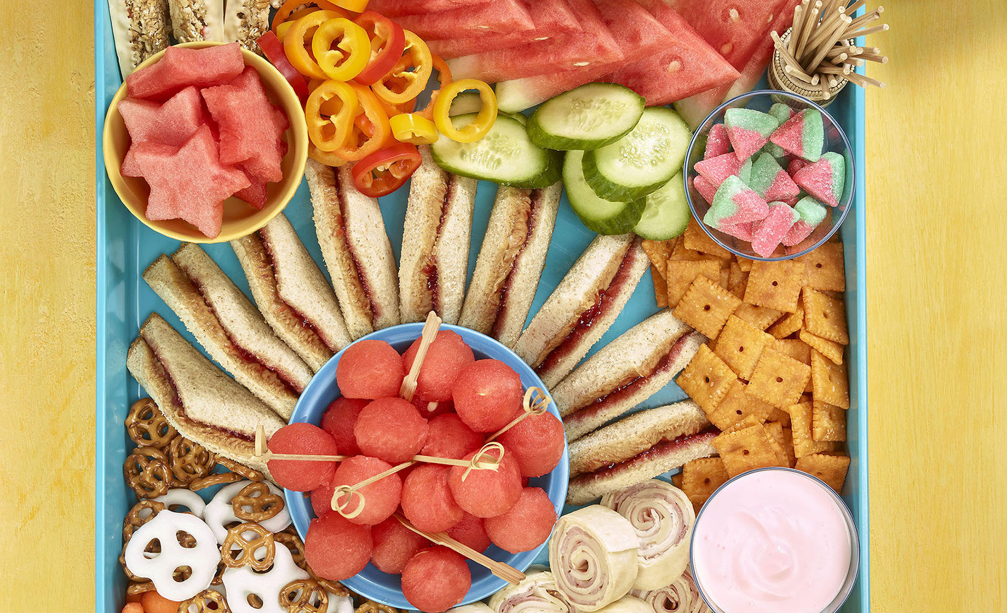 Kids grazing board overhead shot showing sandwiches, cracker, watermelon and other fruit