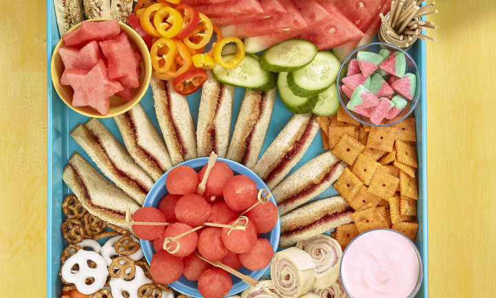 Kids grazing board overhead shot showing sandwiches, cracker, watermelon and other fruit