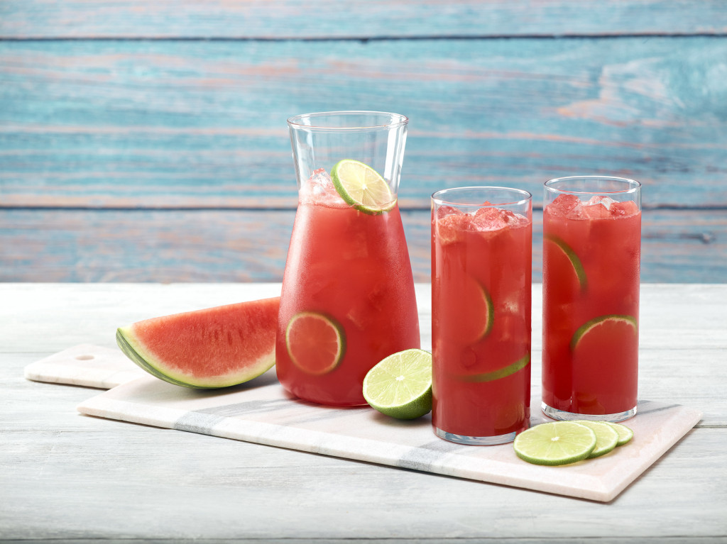 Two glasses of watermelon limeade with pitcher on marble