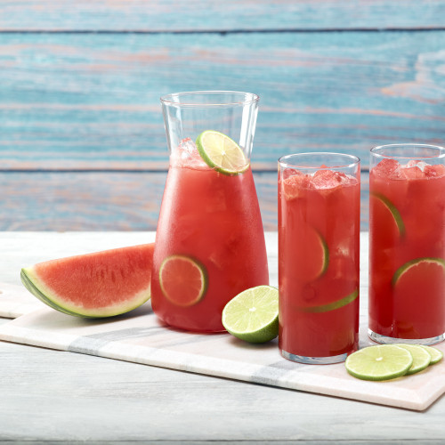 Two glasses of watermelon limeade with pitcher on marble