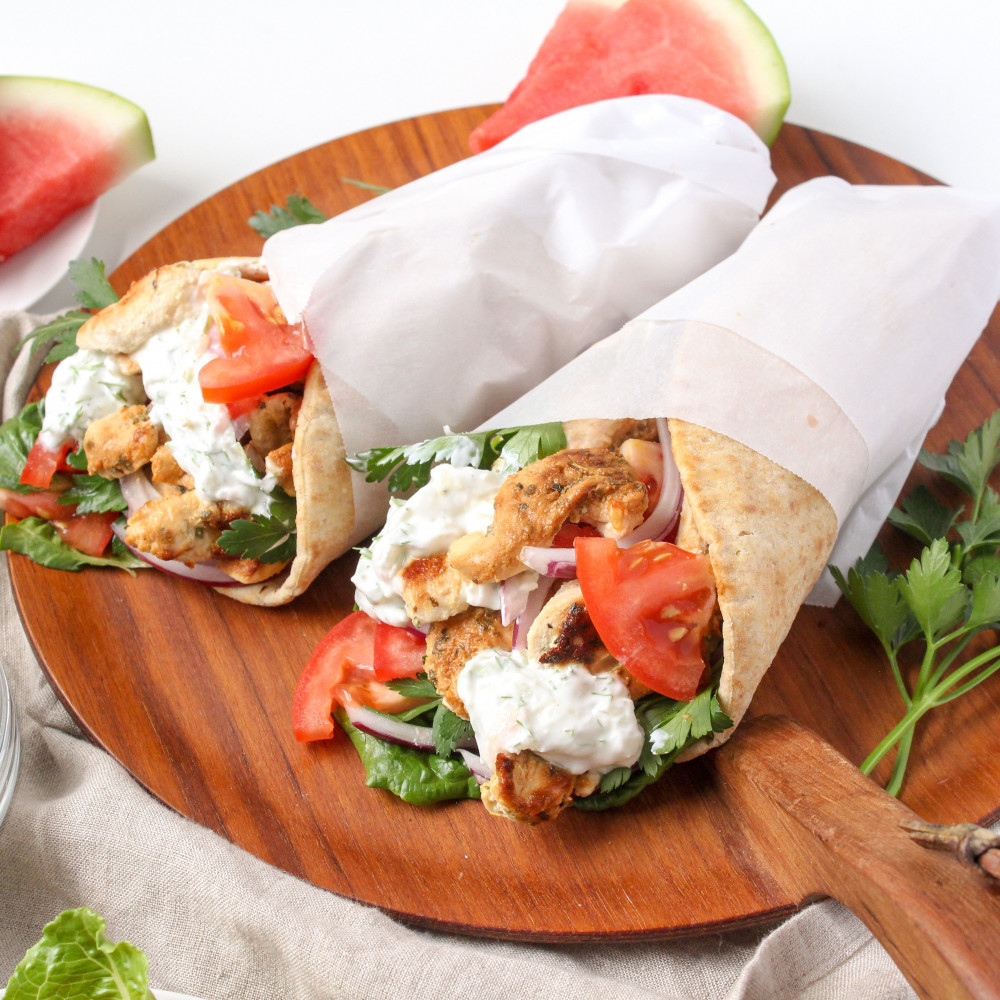 chicken gyros wrapped in paper on wooden serving board
