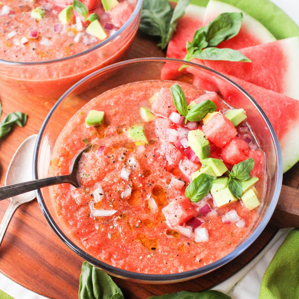 gazpacho in glass bowl garnished with avocado basil and watermelon chunks