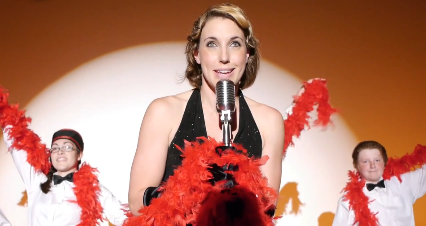 jill wearing a boa singing in an old timey microphone