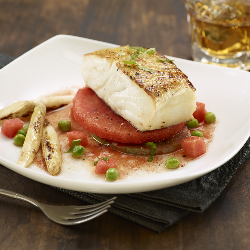 Seared Halibut portion served atop watermelon round with vegetables and vinaigrette