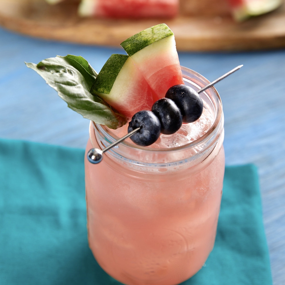 Watermelon Blueberry Basil Lemonade in mason jar with garnishes of basil, watermelon pieces and skewered blueberries